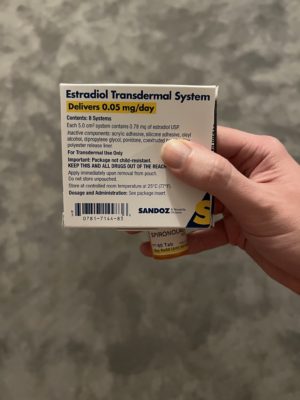 Holding a box of estradiol patches and a bottle of spironolactone.